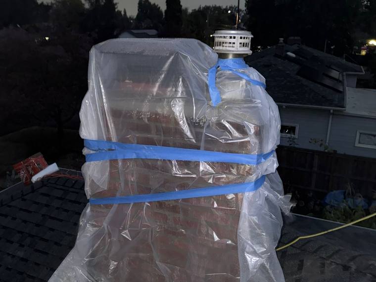 Brick chimney with protective plastic sheeting for masonry repair and rebuild project.